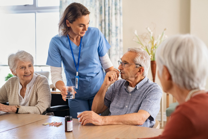 En helsearbeider snakker med en eldre mann og to eldre kvinner